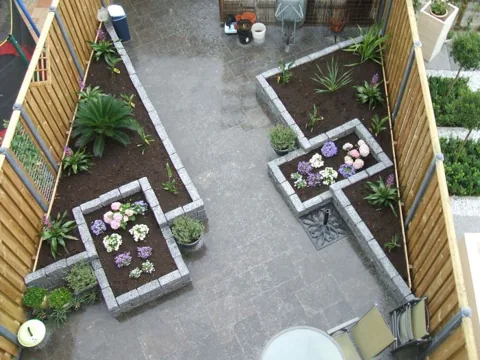 Nieuw aangelegde achtertuin met verhoogde borders, bestrating en jonge beplanting