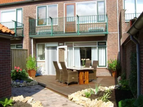 Achtertuin in Rozenburg: vlonder met eettafel en bloeiende borders