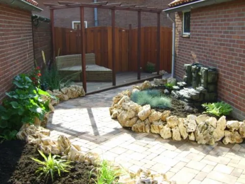 Vijverpartij met natuurstenen rand en beplanting in een achtertuin in Rozenburg